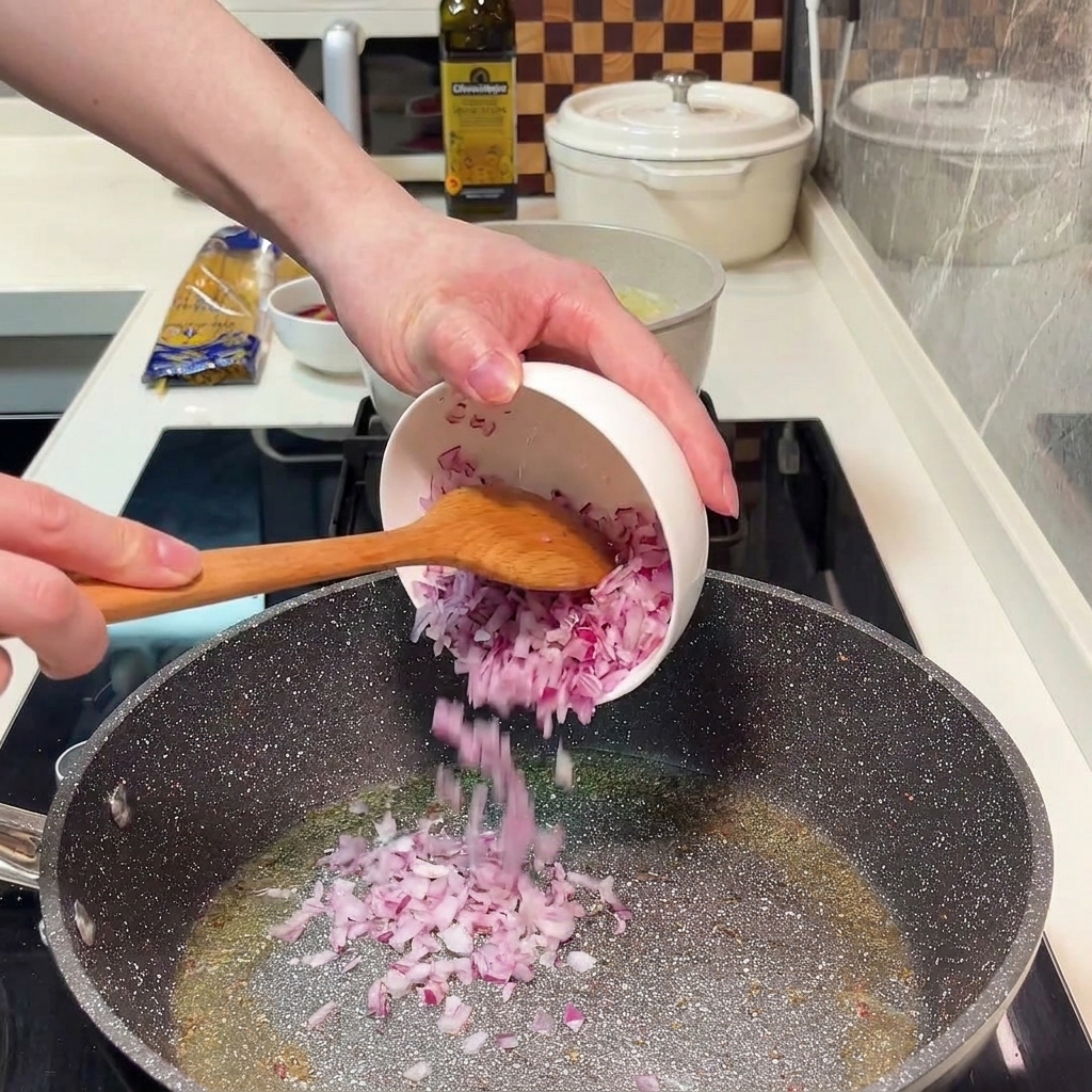 Chopped red onion sautéing in a pan with olive oil.