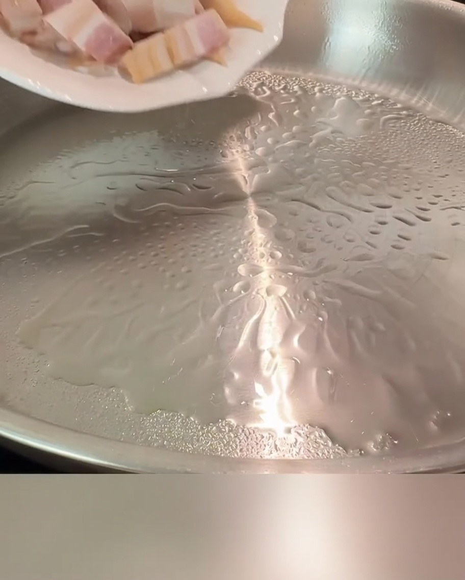 Bacon pieces sizzling in a hot skillet until golden and crispy.