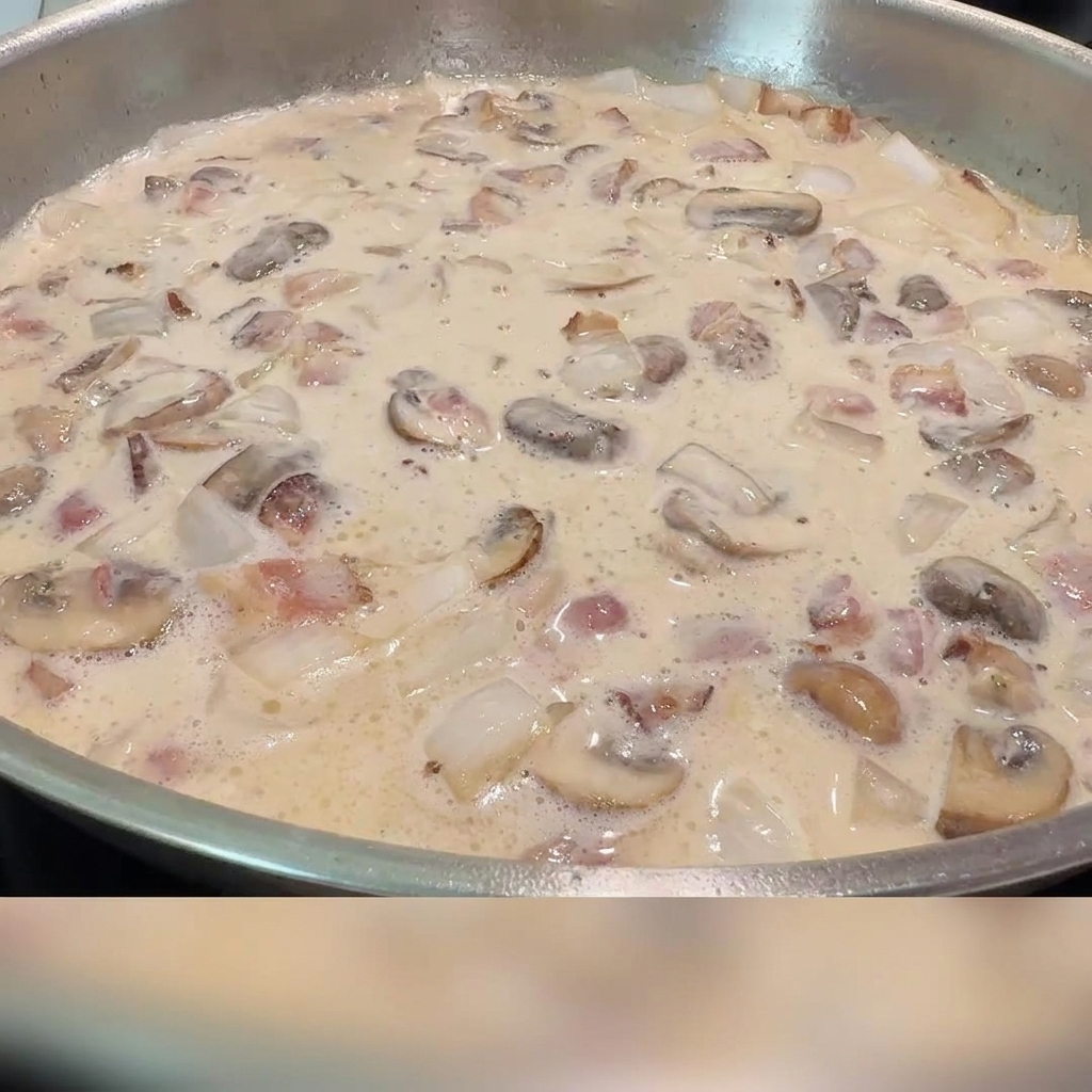 Salt and black pepper being sprinkled into the creamy bacon and mushroom sauce.