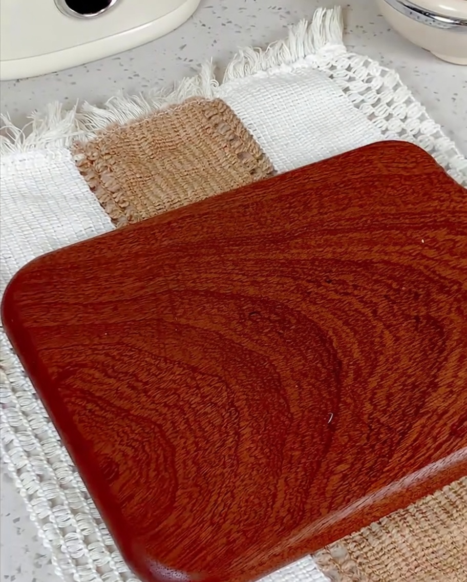Sausage link being sliced into small rounds on a wooden cutting board.