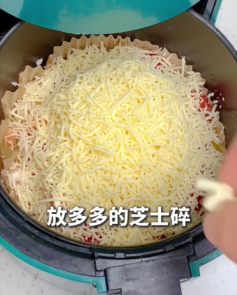 Shredded cheese being spread over the top of the pizza assembly in the air fryer.