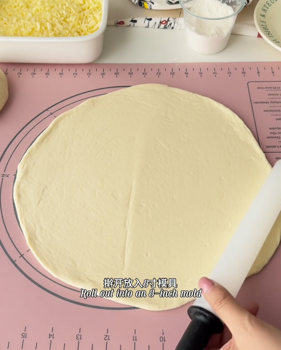 The rolled pizza dough being fitted into a 6-inch metal baking mold.