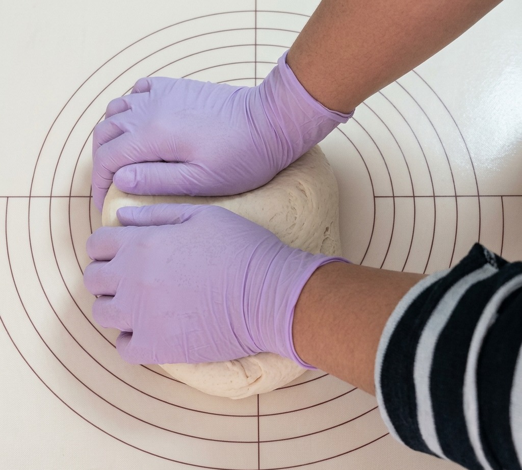 A portion of dough being carefully divided into even segments on a silicone baking mat.