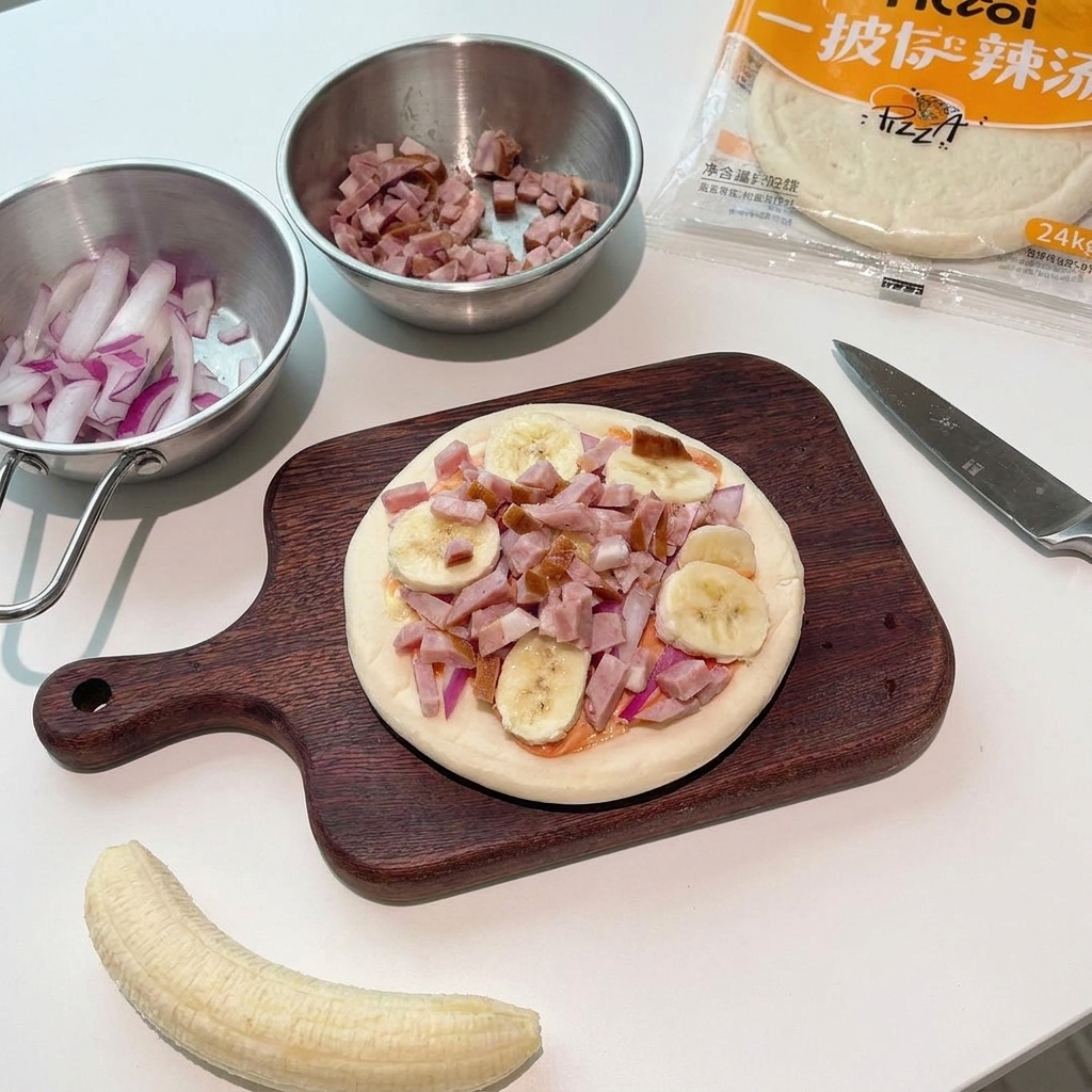 Small pieces of raw bacon being sprinkled over the banana and onion topped pizza.