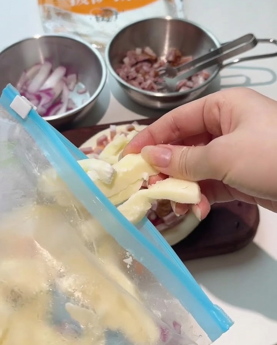 Thick strips of mozzarella cheese being placed over the topped pizza base.