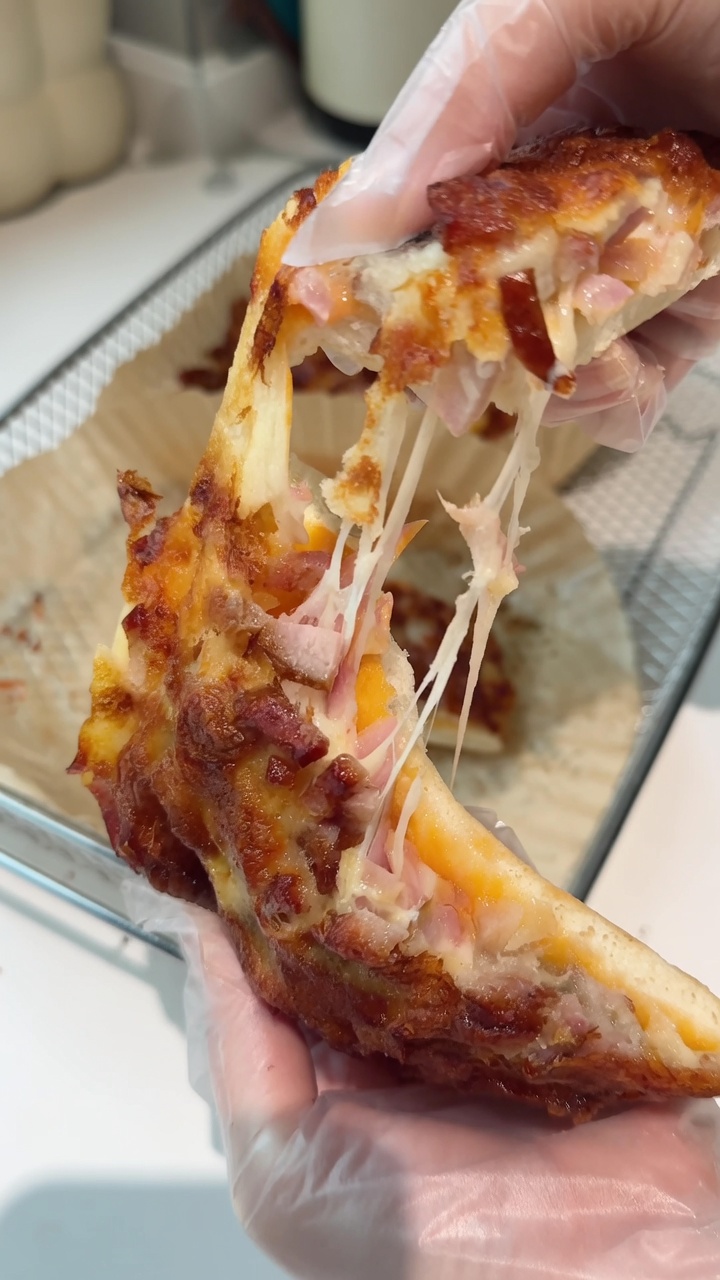 A freshly baked mini pizza pulled apart to reveal a satisfying, stringy mozzarella cheese pull.
