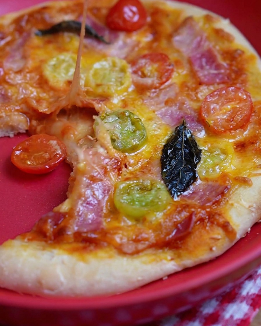A metal spoon spreading vibrant red pizza sauce over the center of a raw pizza dough base.