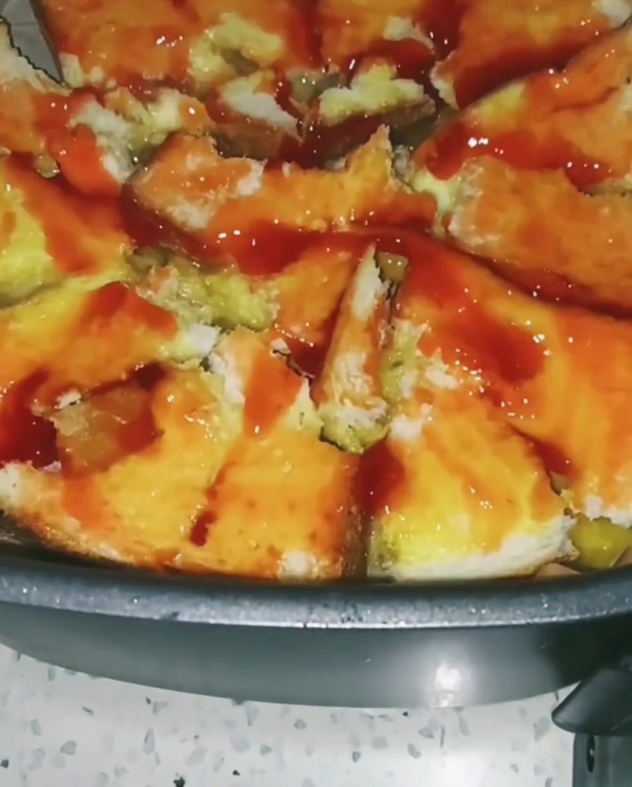 Colorful mixed vegetables like corn and peas being sprinkled over the tomato sauce-coated toast base.