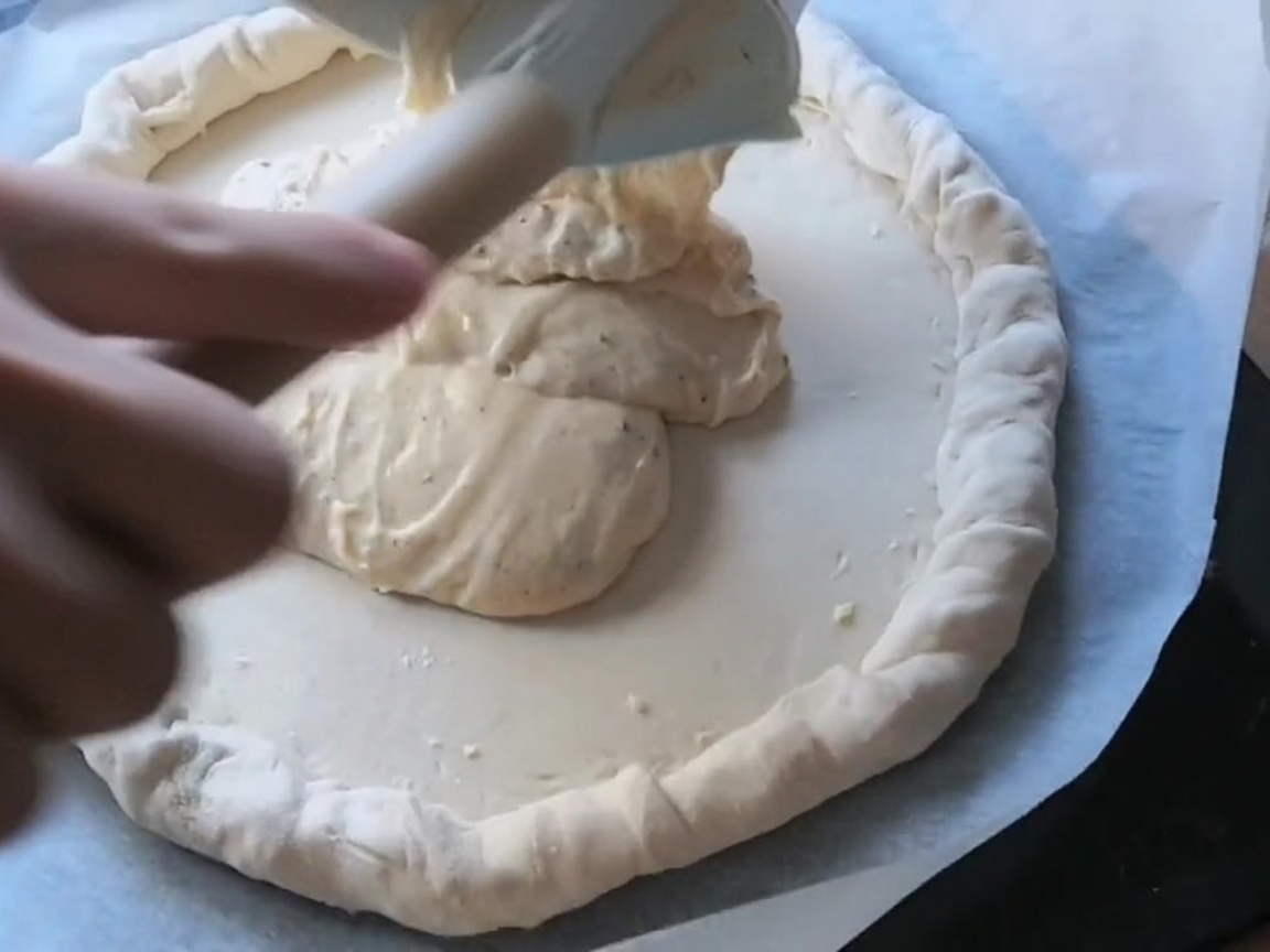 Pepperoni and salami slices arranged on a sauce-covered pizza dough.