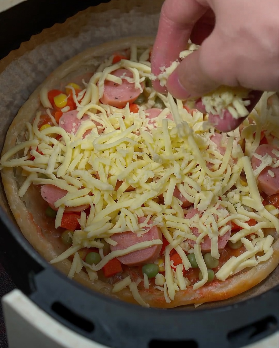 A close-up shot of mozzarella cheese being sprinkled over the pizza ingredients.