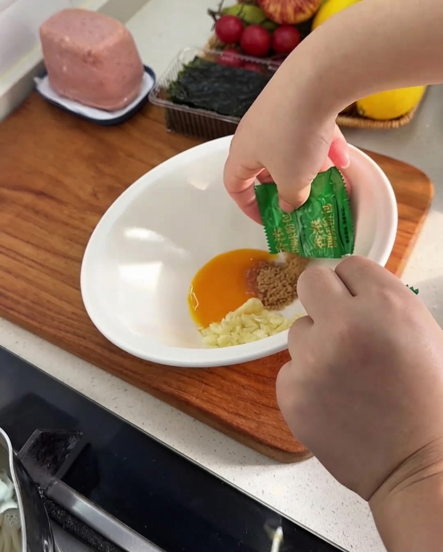 Dry seasoning powder being poured from a small green sachet into the mixing bowl.