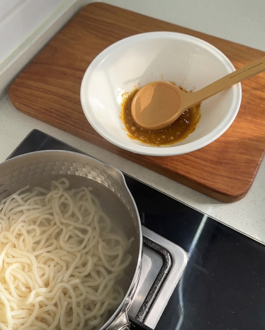 Hot water being poured into the bowl, creating a rich-looking, opaque soup base.