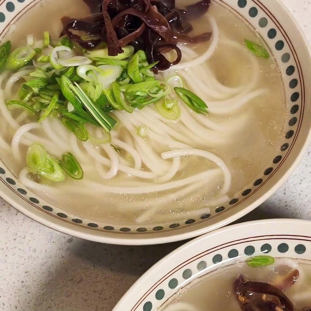 A nearly complete bowl of ramen topped with stir-fried meat, mushrooms, and green onions.