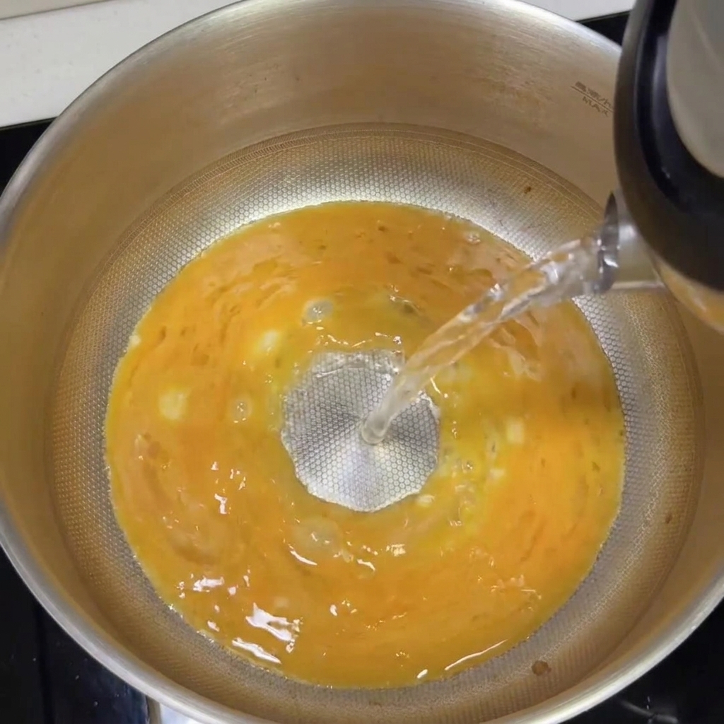 Boiling water being poured into the pot with the tonkotsu base, turning it into a creamy white broth.