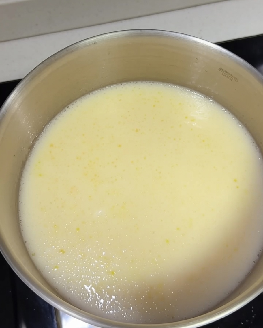 Cooked ramen noodles being added into a pot of boiling creamy tonkotsu broth.