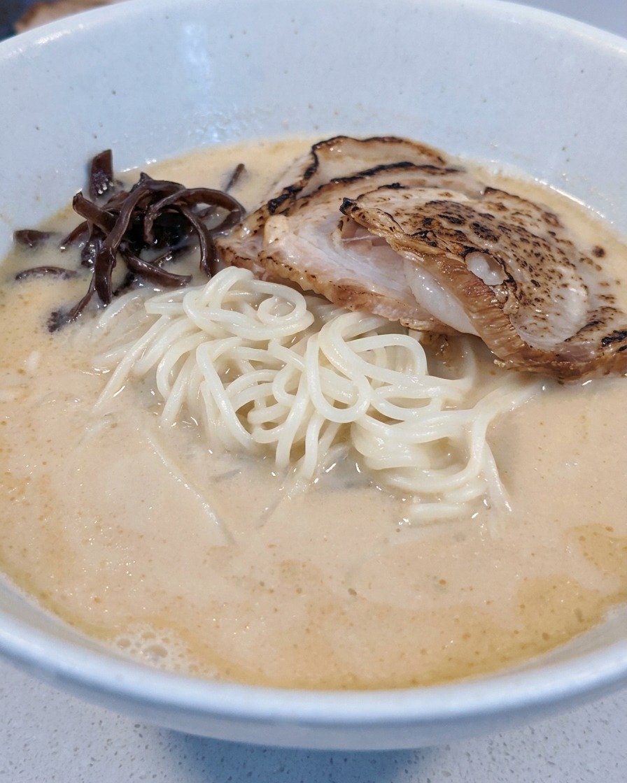 Wood ear mushrooms and bamboo shoots being arranged in the ramen bowl.