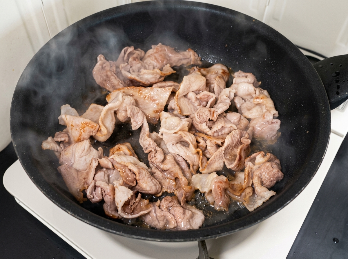 Chopped kimchi and sugar mixed with the cooked pork in the pan.