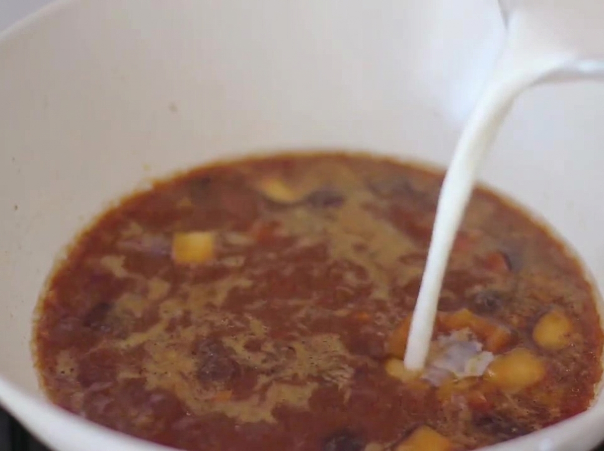 Milk being poured into the miso-based broth in the pan.