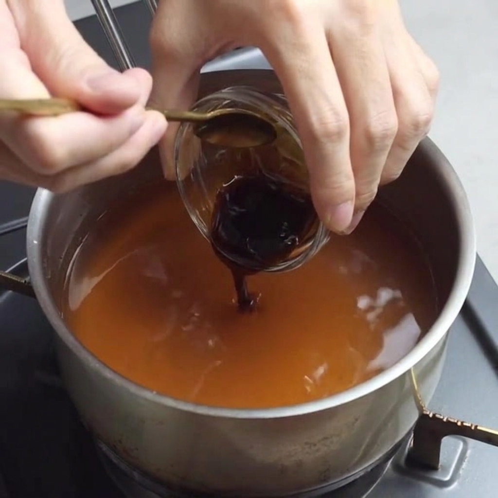 Adding oyster sauce to the ramen broth mixture.