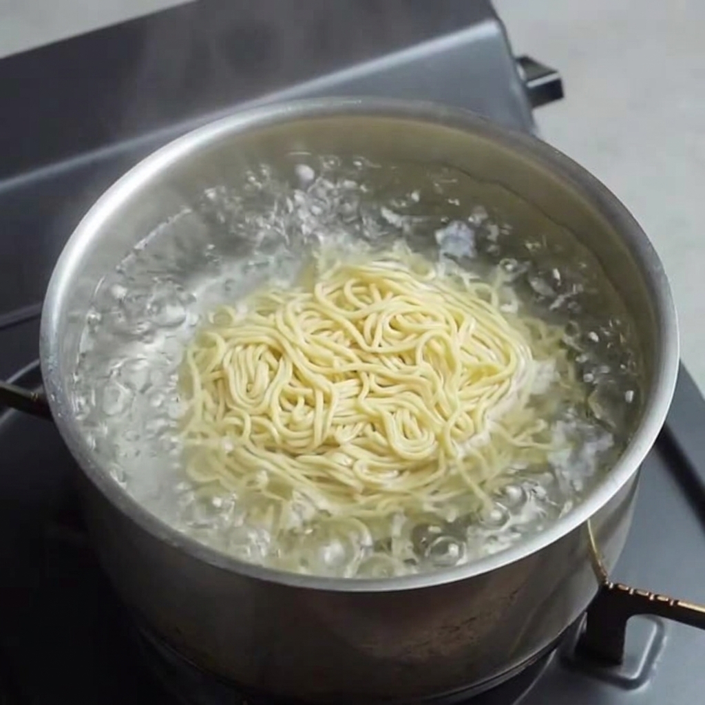 Fresh yellow ramen noodles cooking in boiling water.
