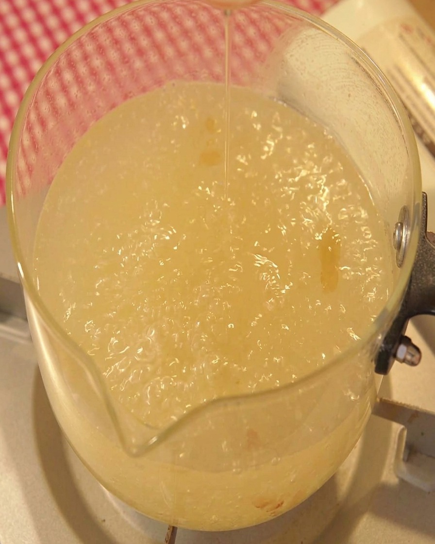 Sesame oil being poured into a boiling pot of broth.
