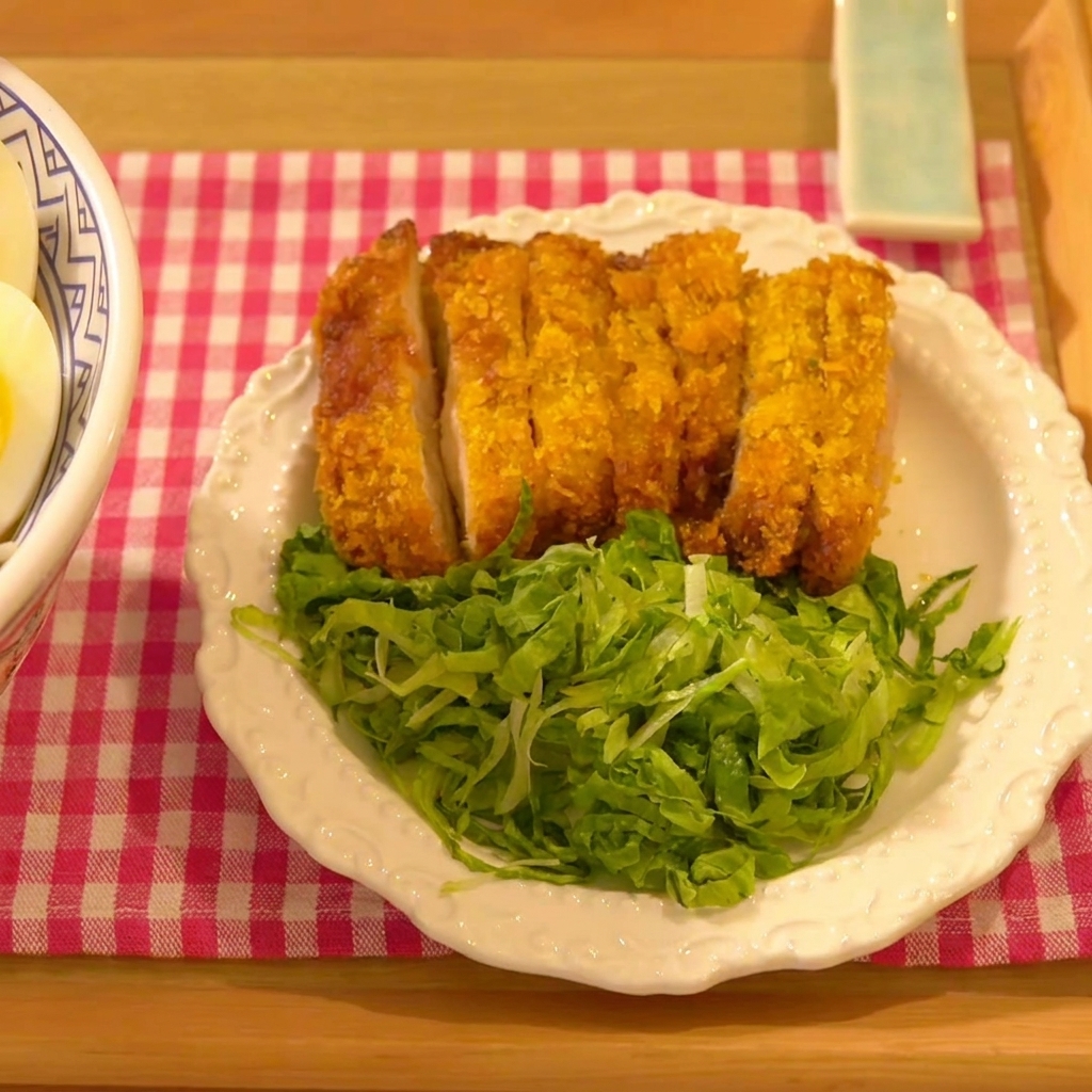 The chicken cutlet being pressed firmly into a bed of panko breadcrumbs.