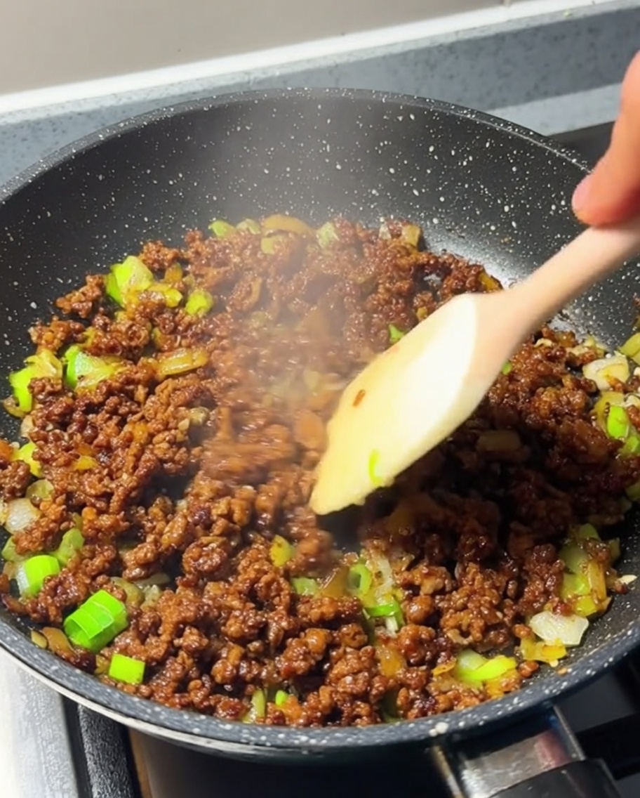 Minced meat being actively stirred in a pan, now fully browned and fragrant.
