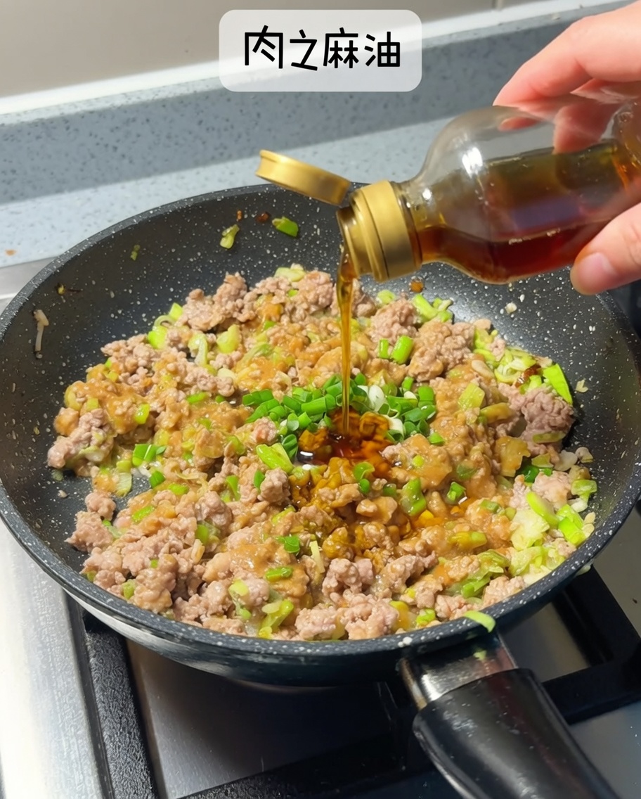 Dark golden sesame oil being poured from a small glass bottle into the pan with the browned meat and miso mixture.