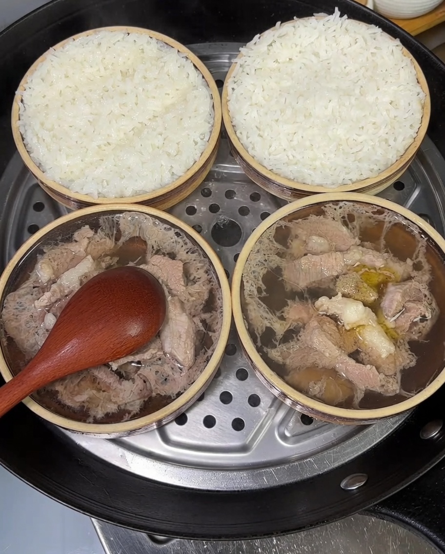 Two small bowls of steamed pork and rice garnished with vibrant, freshly chopped green onions.
