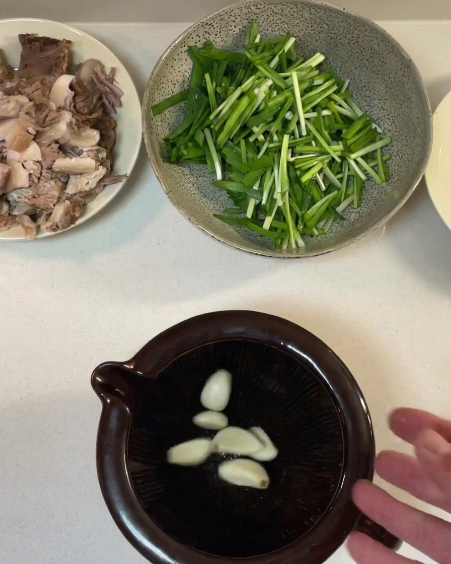 Garlic cloves being crushed into a paste inside a dark ceramic mortar.