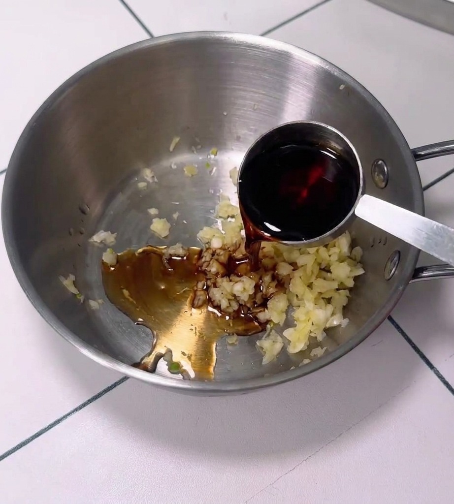 A bowl containing a mixture of garlic, chili paste, and other sauce ingredients.