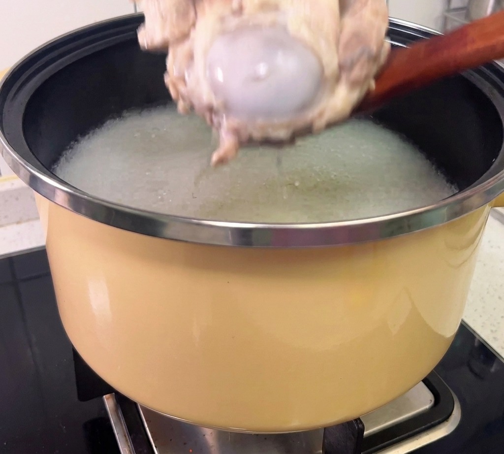 Meat being shredded from cooked pork bones while wearing gloves.