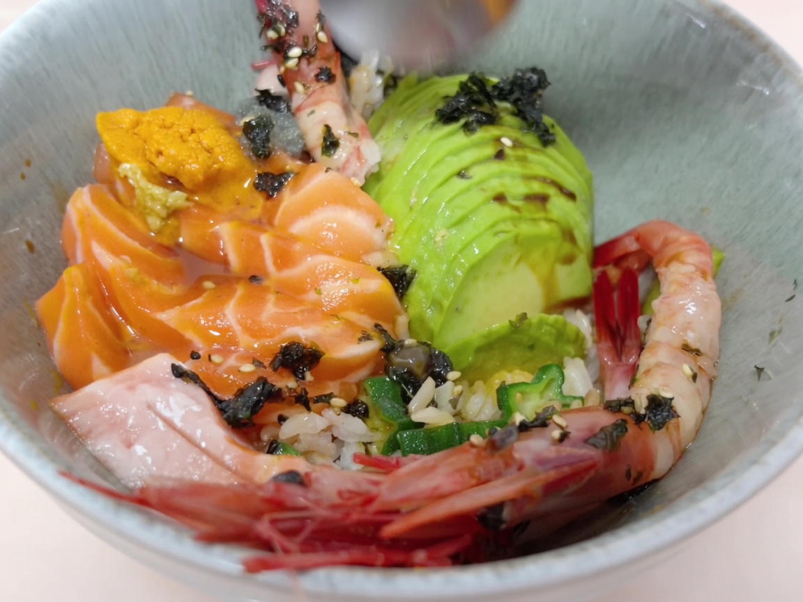 Fresh sea urchin being carefully added to the rice bowl with a spoon.