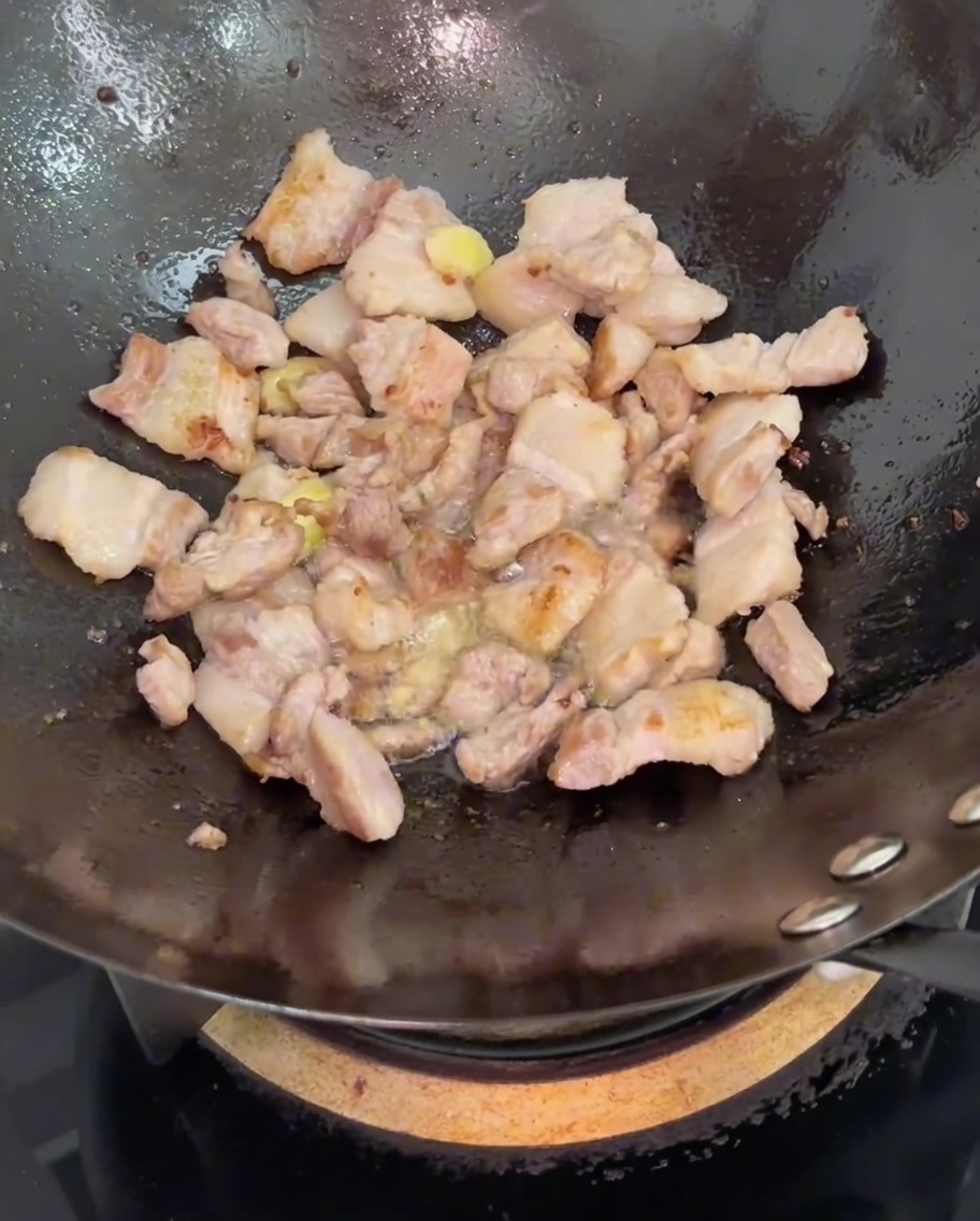 Soy sauce being poured into the wok over the stir-fried pork belly and ginger.