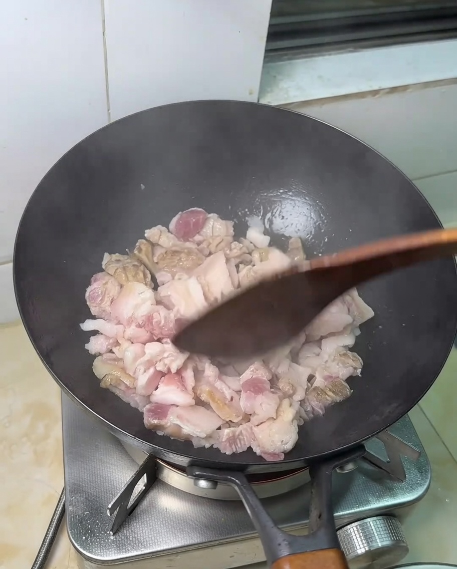 Slices of raw pork belly frying in a hot pan.