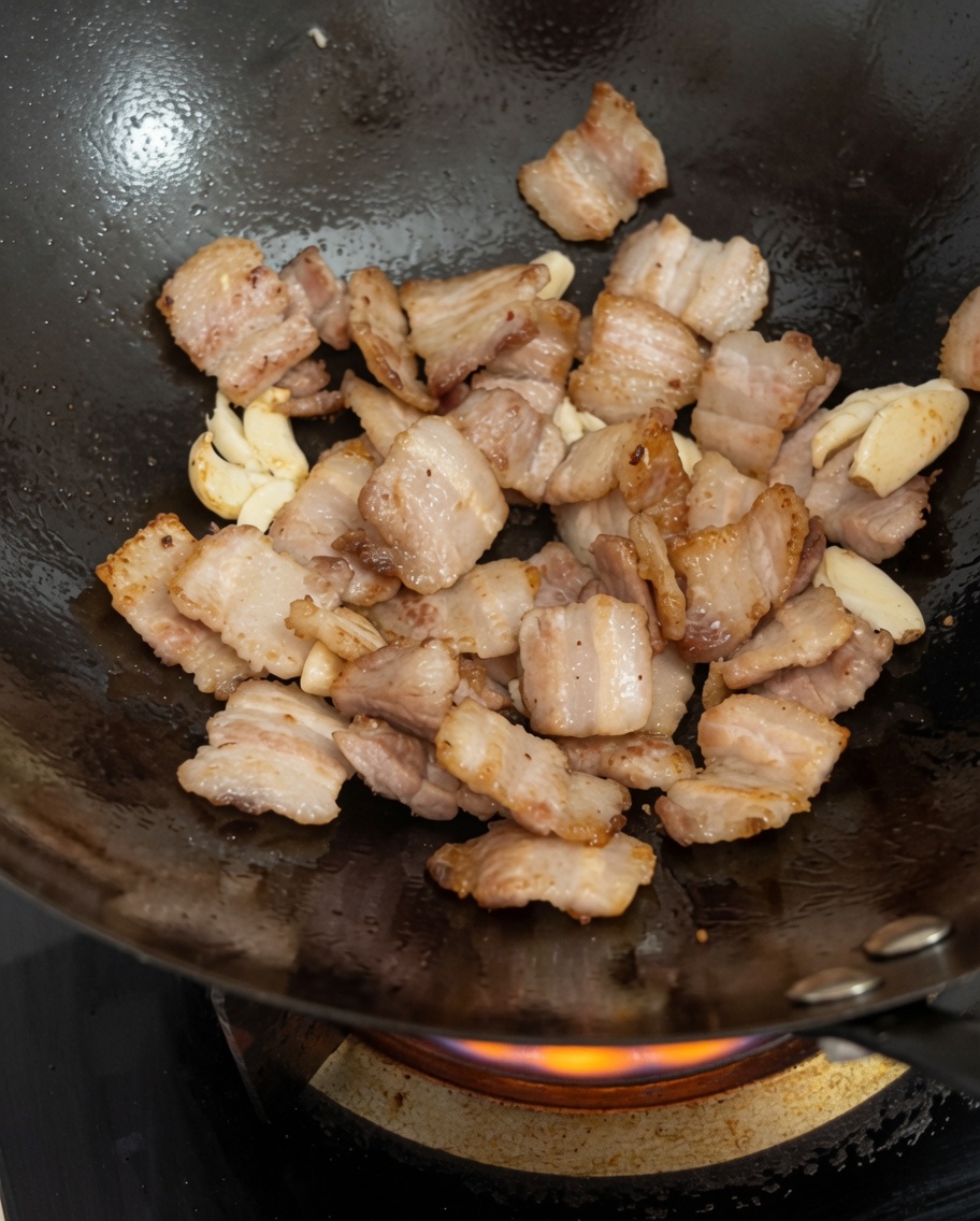 Fermented black beans being tossed into the wok with the pork and garlic.