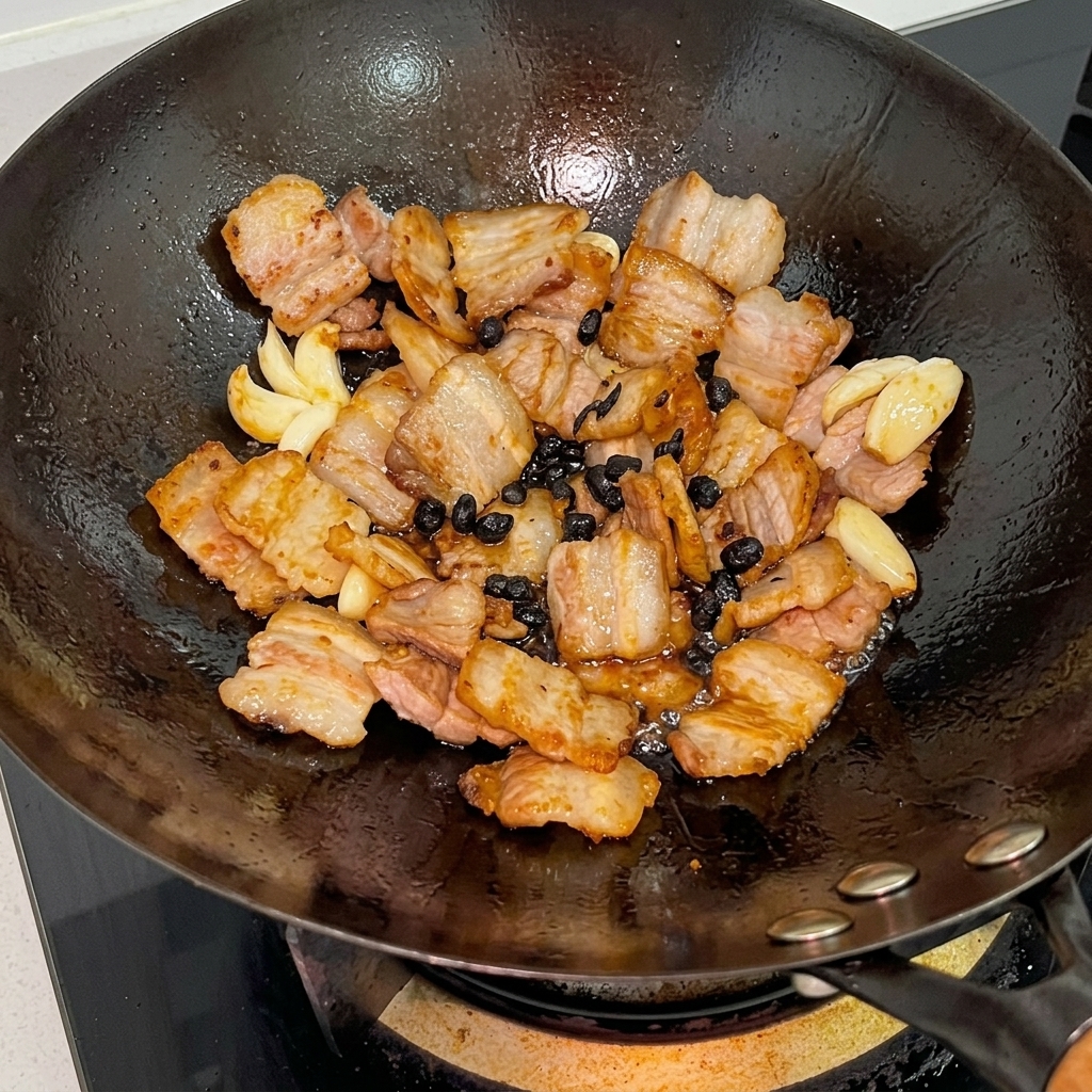 Oyster sauce and soy sauces being poured over the pork mixture in the wok.
