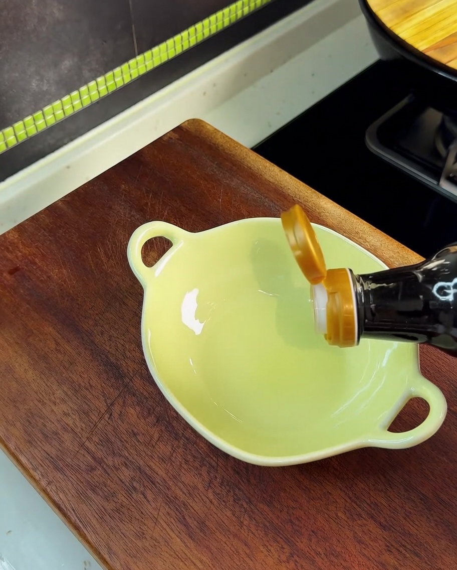 Soy sauce being poured into a small yellow bowl containing salt, MSG, and sugar.