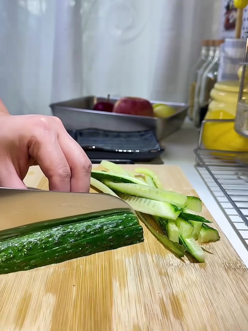 Thin cucumber strips neatly arranged on a wooden cutting board.