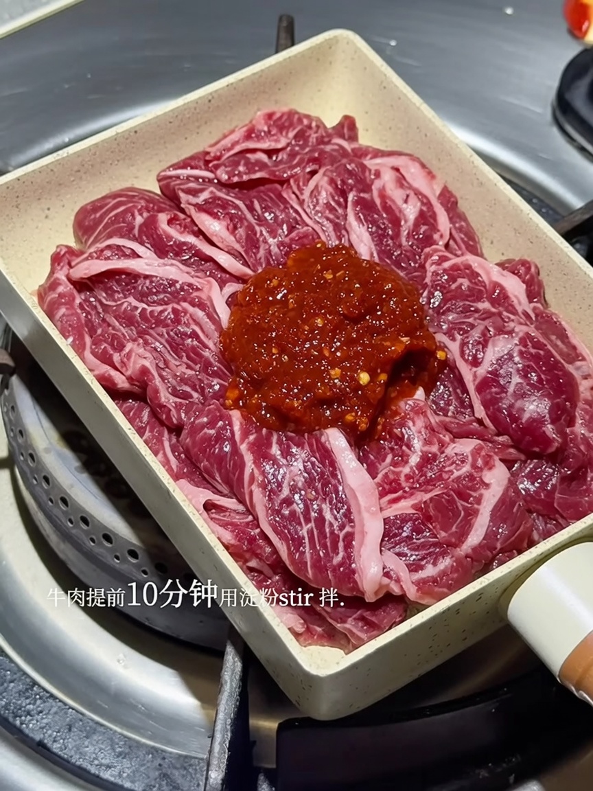 Sizzling beef strips in a pan, heavily coated in a rich, spicy red Korean sauce.