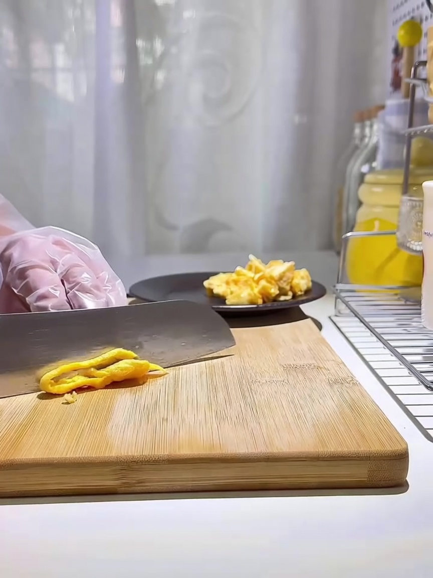 A stack of golden-yellow egg strips resting on a wooden cutting board.