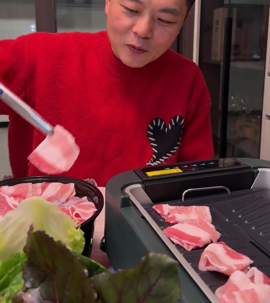 Thin pork belly slices cooking on a hot electric grill surface, turning golden brown.