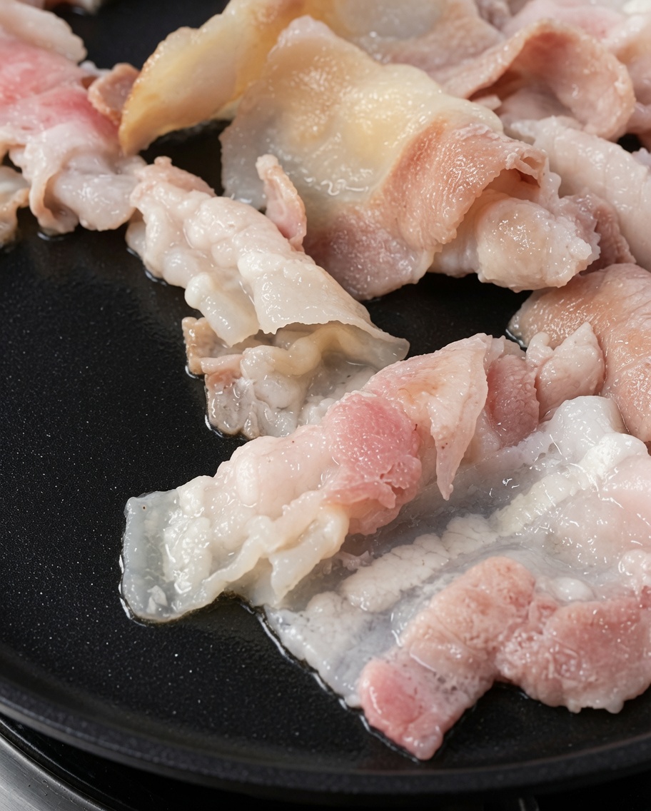 Golden brown grilled pork belly slices on a hot griddle.