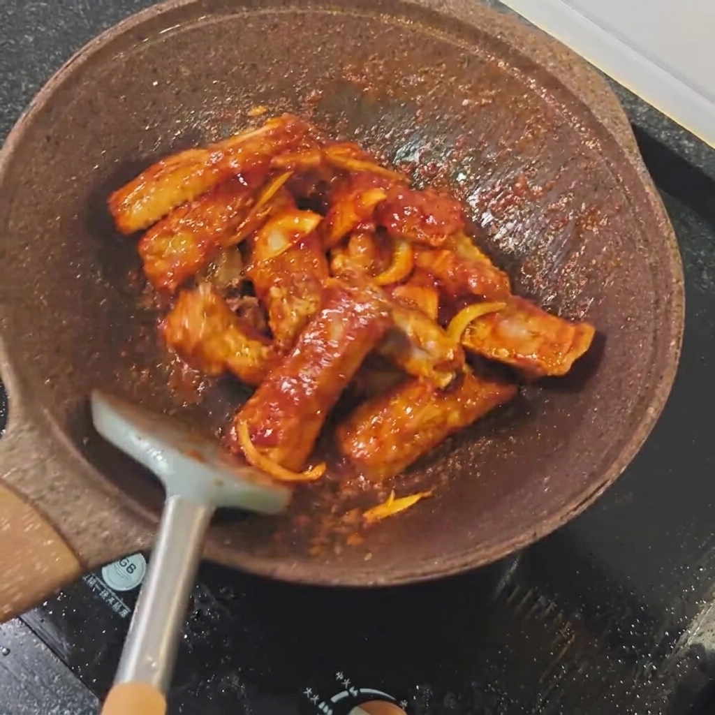 Light soy sauce being poured over pork ribs in a pan.