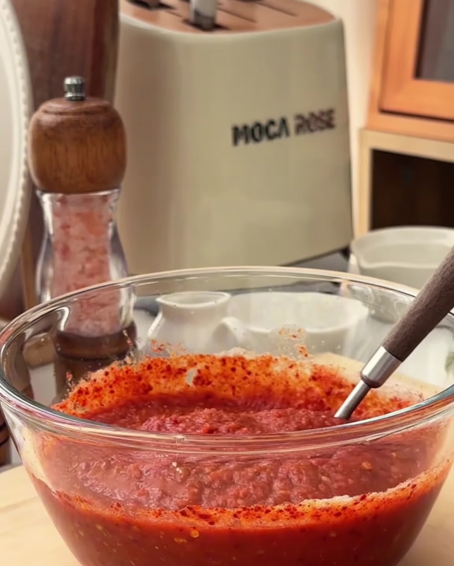 A close-up view of the spicy marinade ingredients being stirred together in a glass bowl.