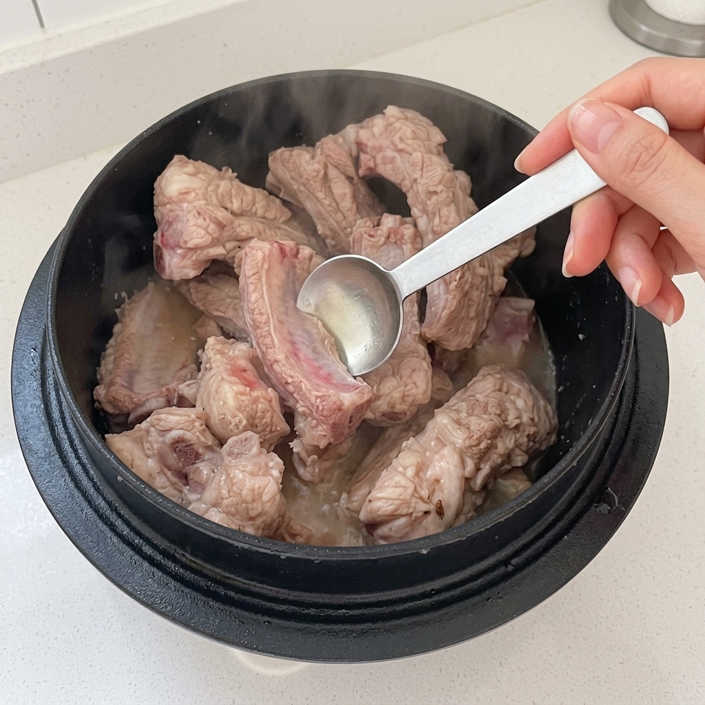 Vinegar being added to a pot of stir-frying pork ribs.