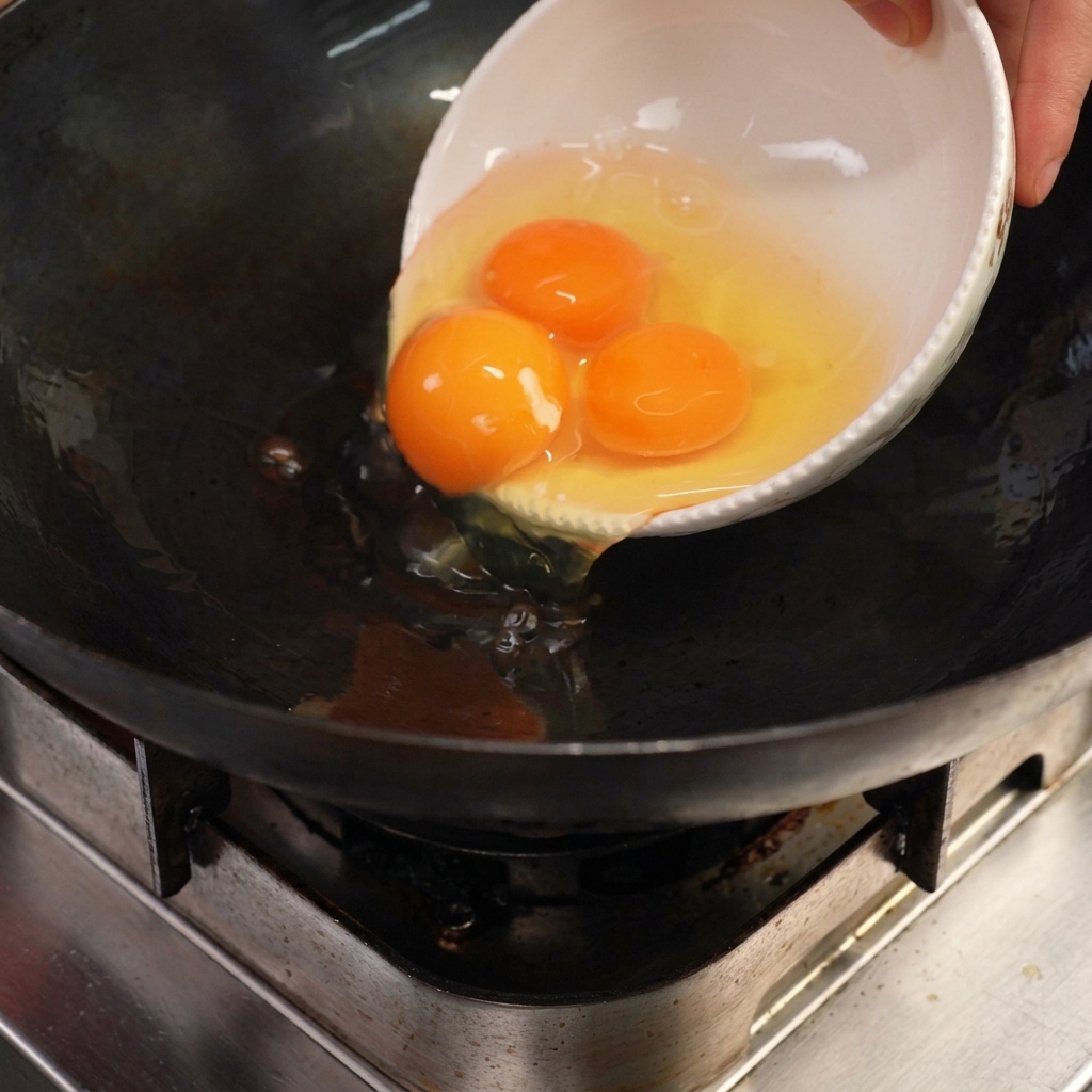 Eggs sizzling in a wok with hot rendered lard.