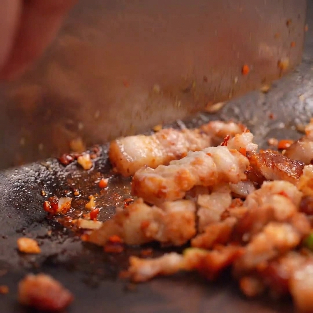 Fried eggs being crushed into a rustic, chunky paste inside a stone mortar.