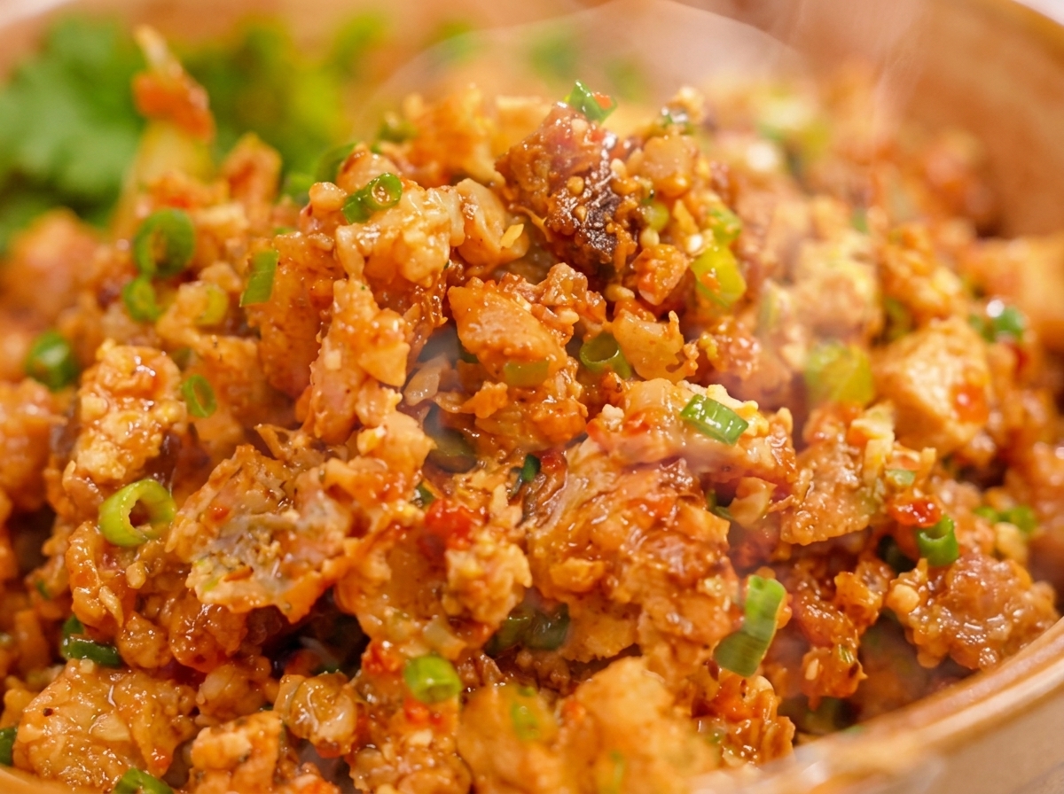 A spoonful of seasoned meat and egg filling being placed onto the center of a round dumpling wrapper ready for sealing.