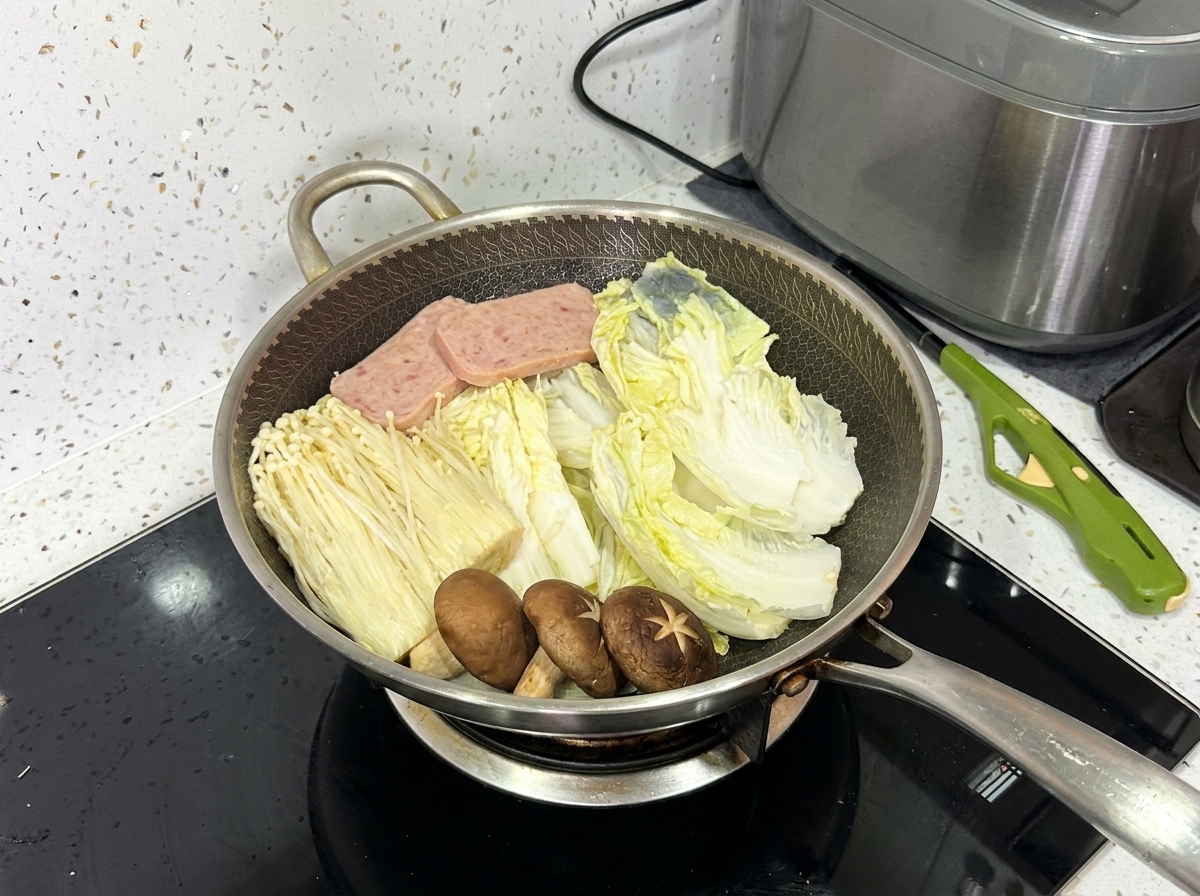 A fully arranged wok containing napa cabbage, enoki mushrooms, shiitake mushrooms, luncheon meat, and pork slices.